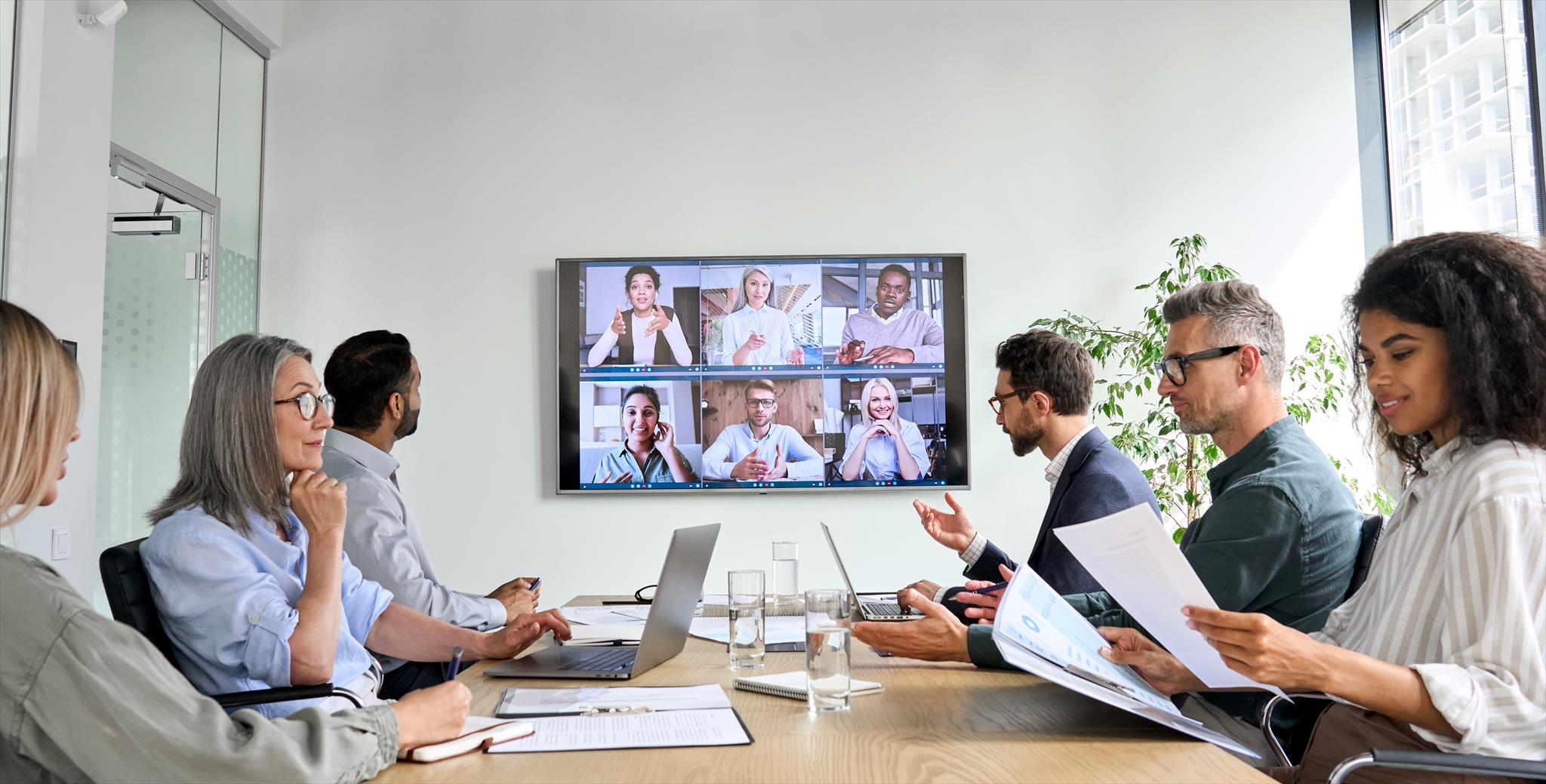 People working together, some in person and some via video call