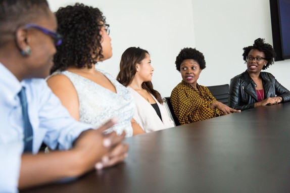 Diverse group of people sitting at a conference table and talking 