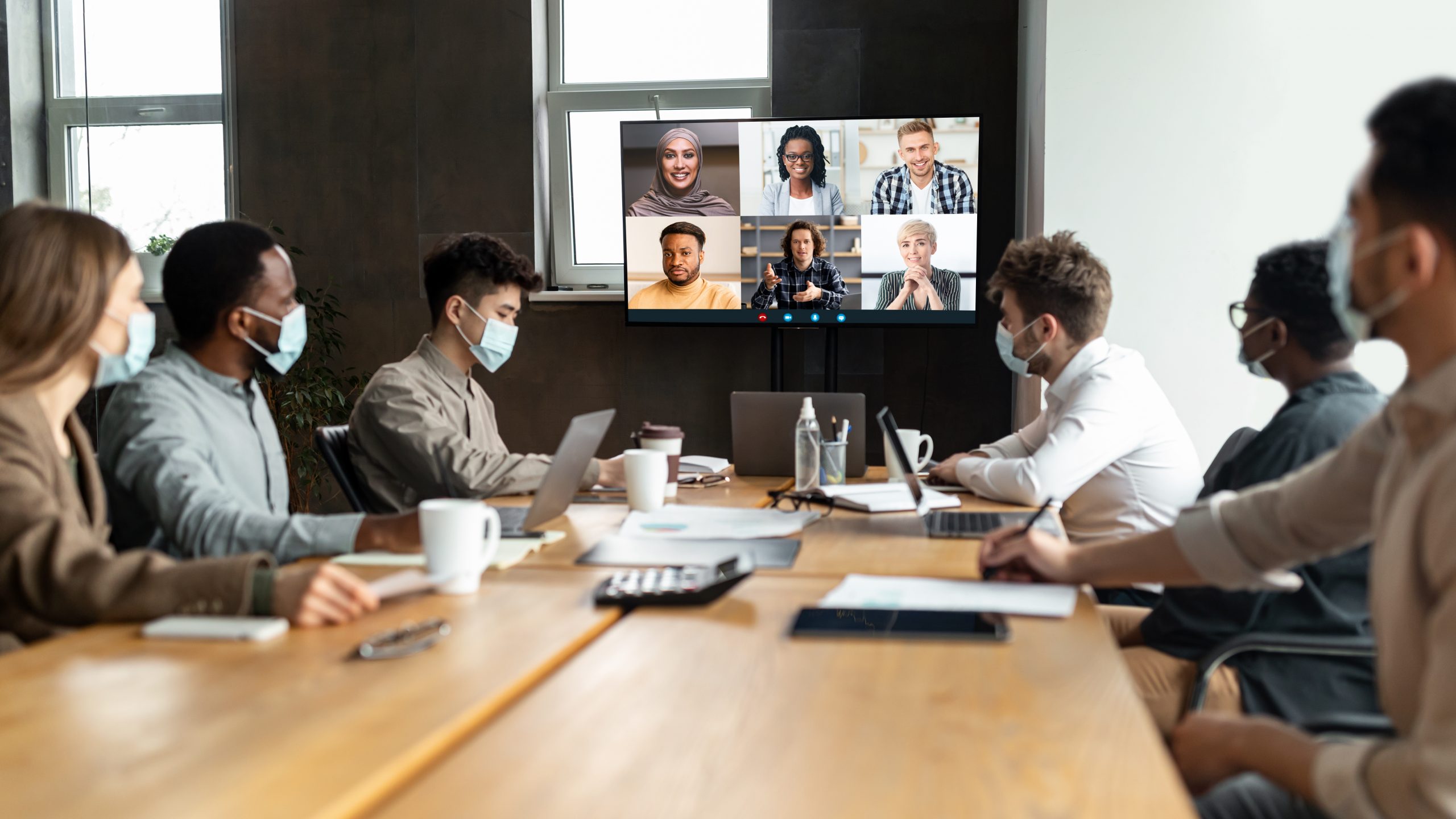 Videoconferencing,,Virtual,Meeting.,Diverse,Group,Of,Workers,In,Masks,Making Diverse group of people wearing masks working together in person having a video conference call