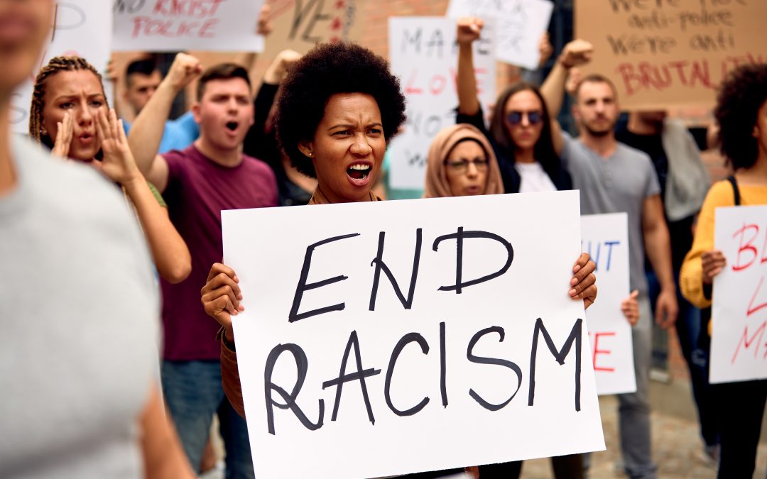 Protesters marching with a sign that says "END RACISM"