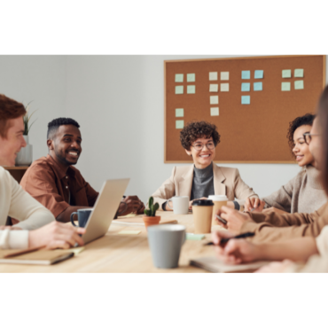 Group of diverse people sitting at a table and smiling as they discuss