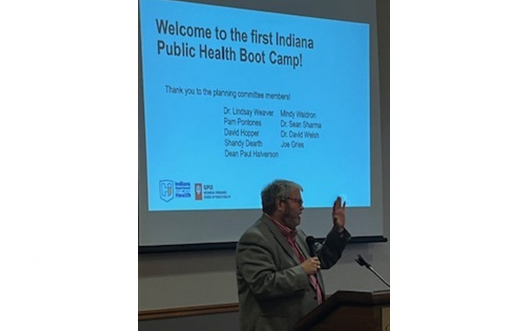 Photo of Dr. Paul Halverson speaking in front of a presentation slide titled, "Welcome to the first Indiana Public Health Boot Camp!"